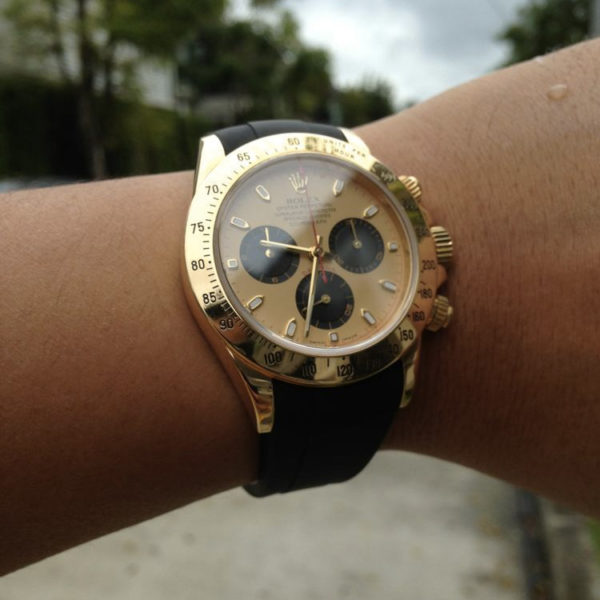 Black rubber strap with golden Rolex watch on wrist